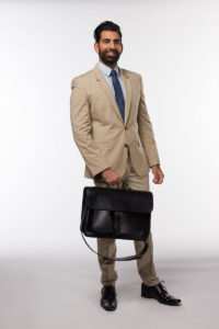 A professional in a tan suit and blue tie holding a Brunswick black leather briefcase