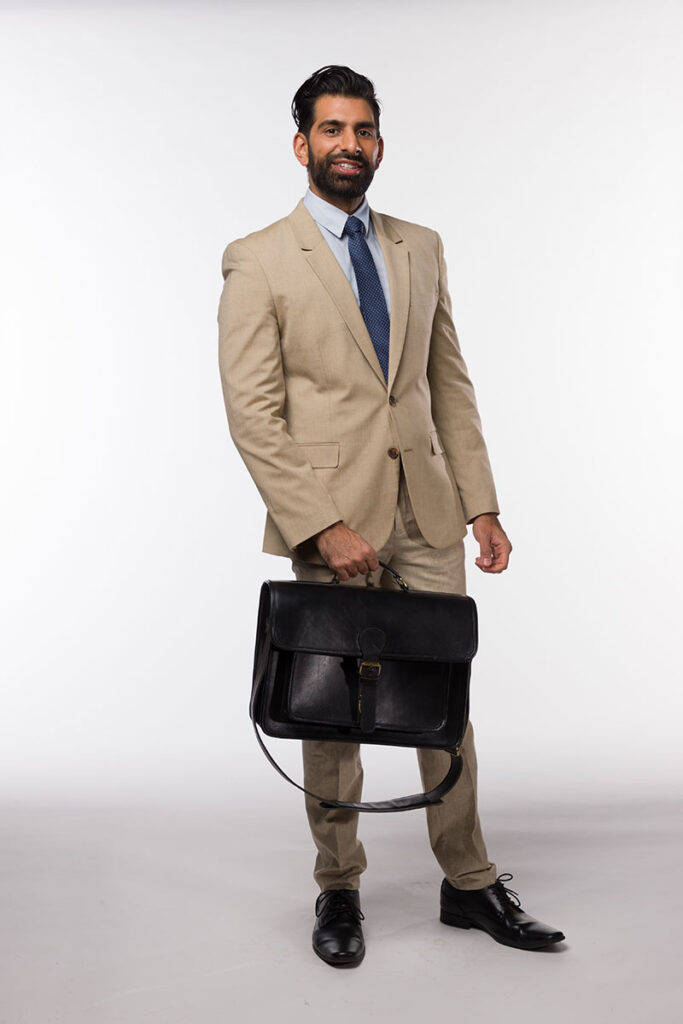 A professional in a tan suit and blue tie holding a Brunswick black leather briefcase