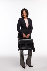A professional woman in a sleek black and gray suit holding a black Brunswick leather briefcase