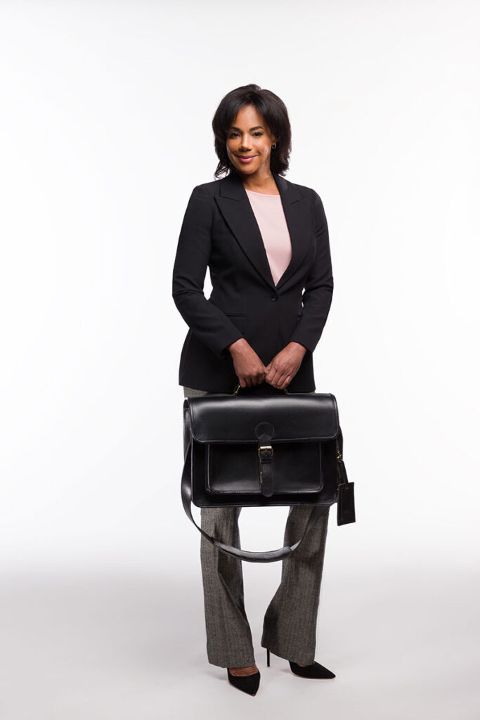 A professional woman in a sleek black and gray suit holding a black Brunswick leather briefcase
