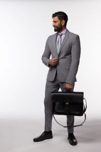 A professional man in a gray suit holding a black Brunswick leather briefcase work bag