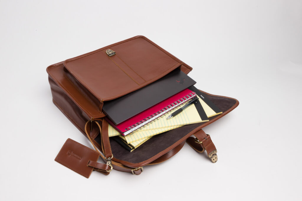 A brown Brunswick leather briefcase, open and showing the legal pads, pens, and laptop carried within
